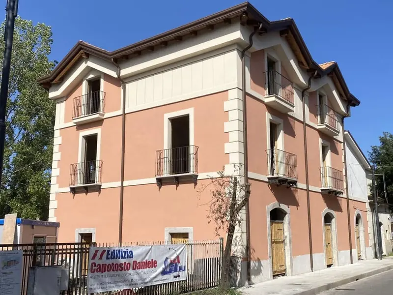 Palazzina ristrutturata con facciata rosa e cornici chiare